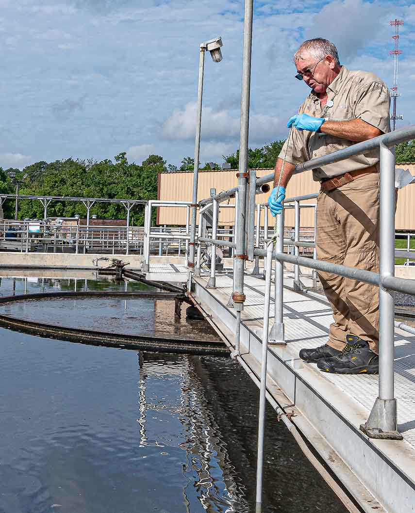 Water Resources male standing on a bridge over a portion of the wastewater treatment process