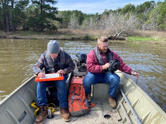 picture of two people in the back of a boat sampling water