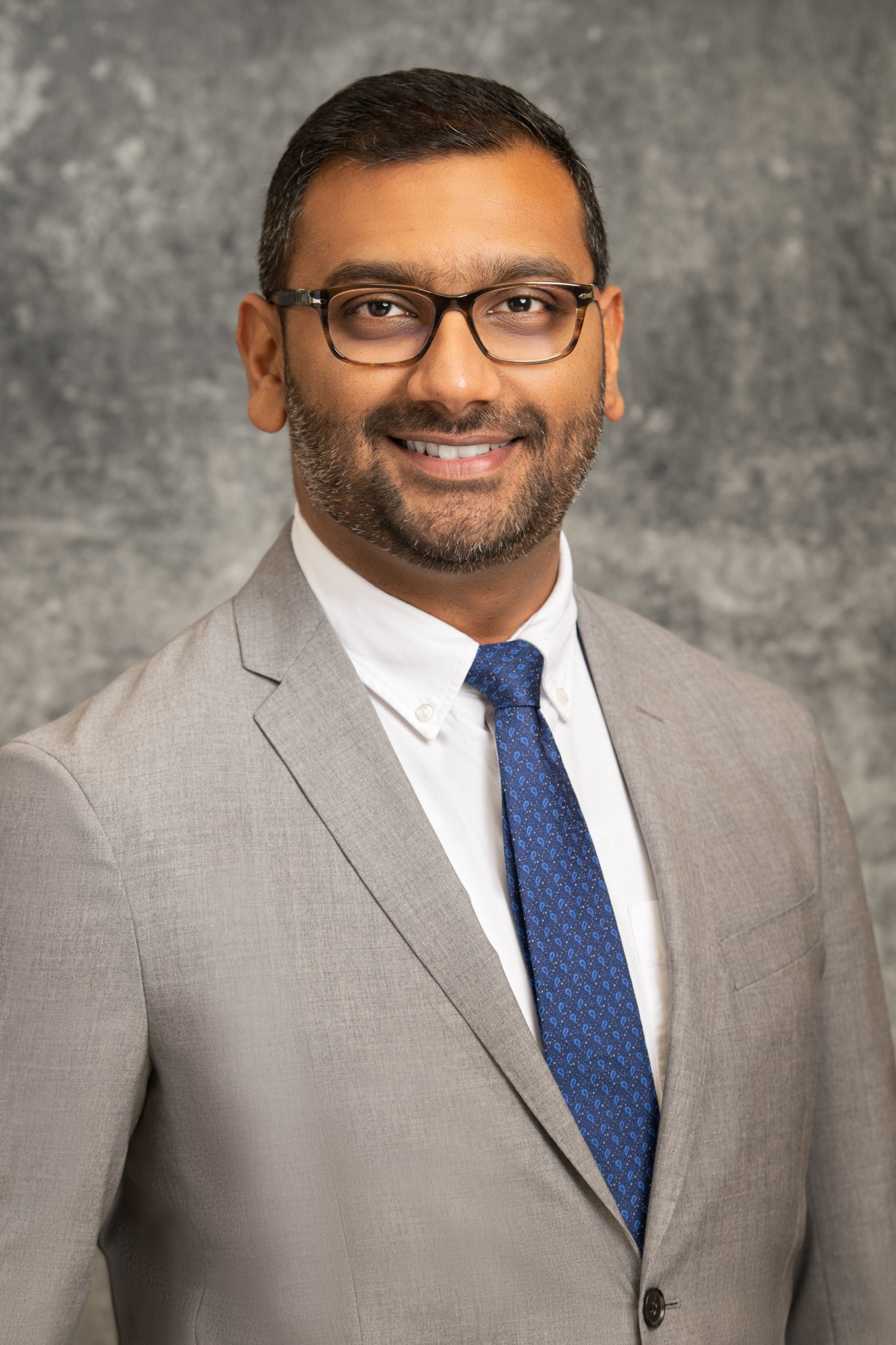 Nabeel Khan Male in gray suit, blue tie, and glasses